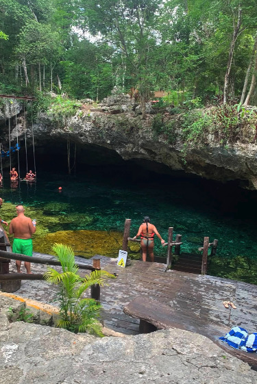 A guided group swimming in the clear water of a Tulum cenote