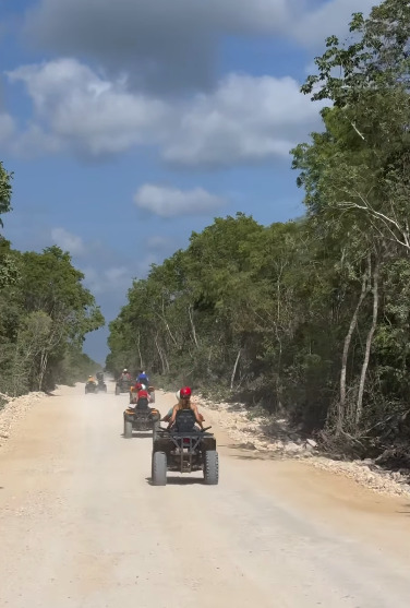 Quad bikes parked on a jungle track beside a cenote